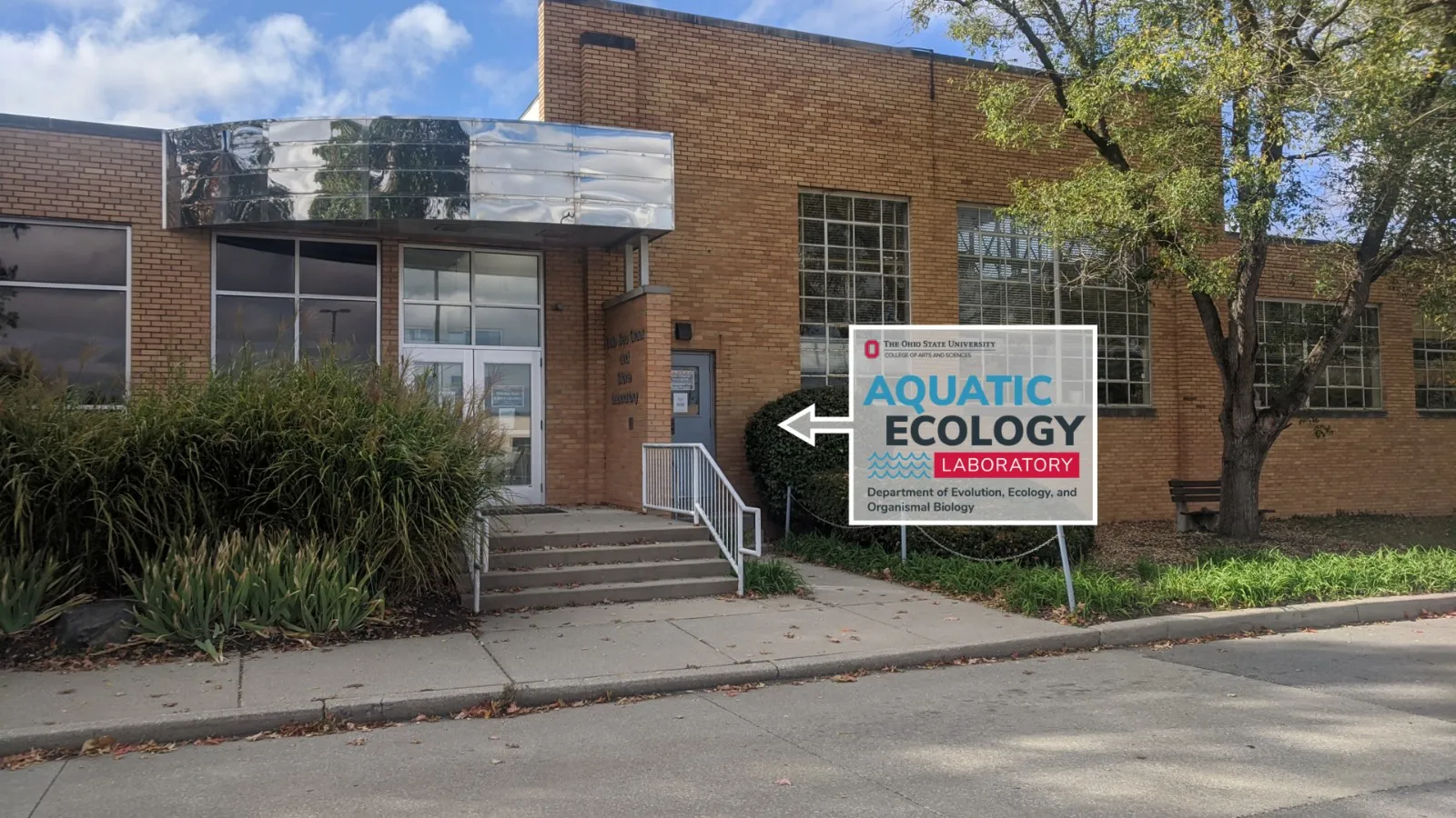 The Research Center building viewed from the driveway with the AEL logo in a arrow box pointing toward the entrance door.
