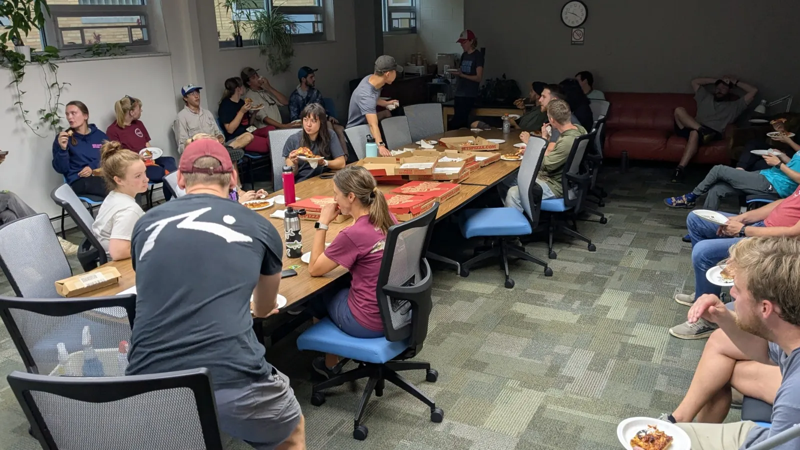 AELers enjoying pizza in the conference room after Work Day